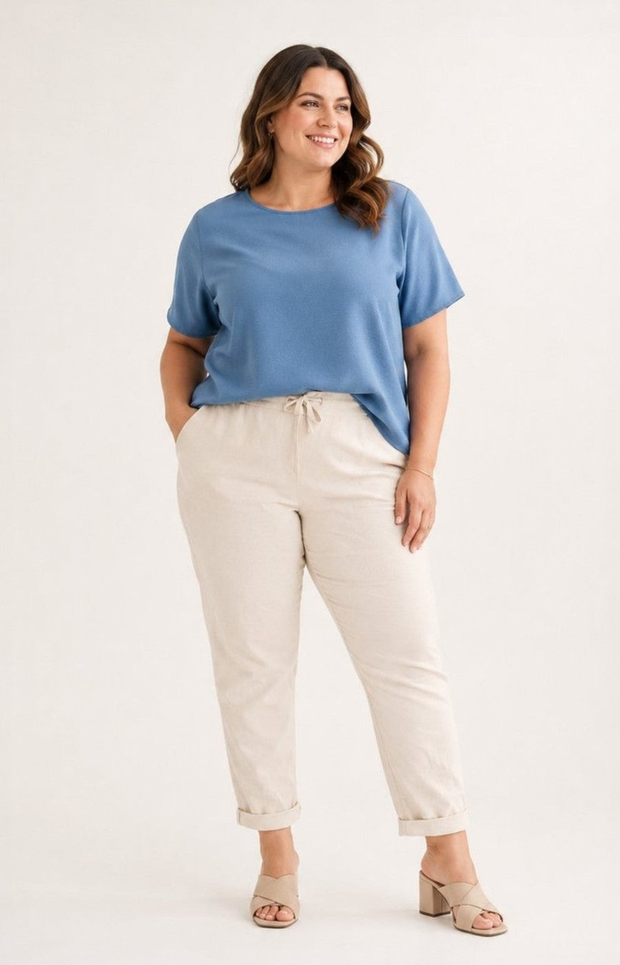 Woman wearing a blue top and beige pants on a white background
