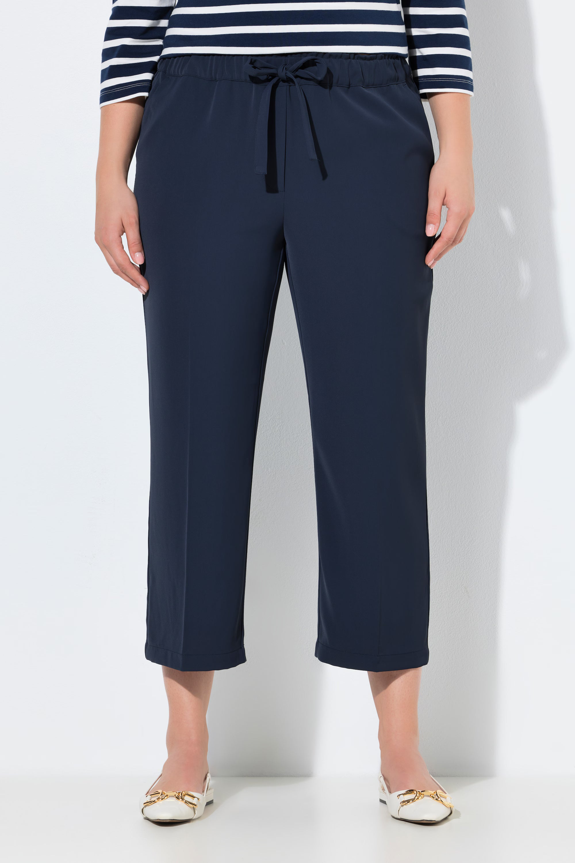 Person wearing the Ulla Popken 7/8th Trousers in Navy with a striped shirt on a white background