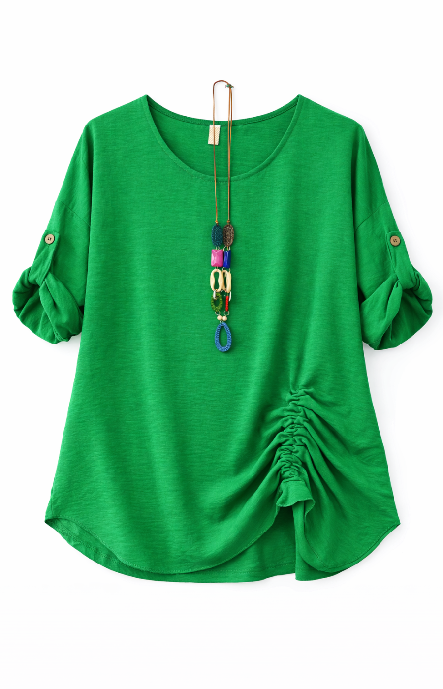 A green blouse with rolled-up sleeves and a gathered detail on one side. Accessorized with a long, colorful pendant necklace.