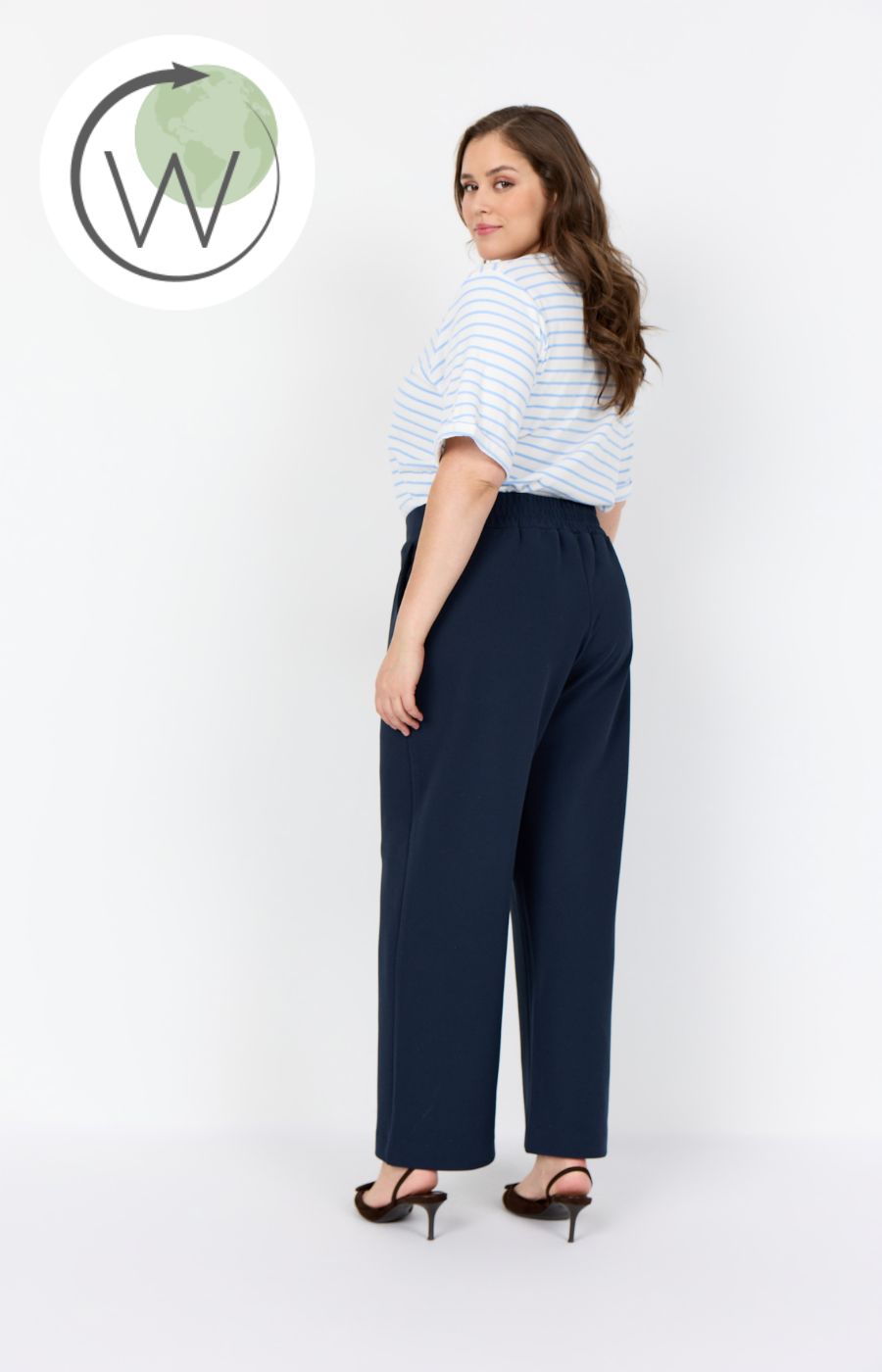 Person wearing the Wasabi Kufa Trousers in Navy, a navy wide-leg  trousers and a striped shirt on a white background 