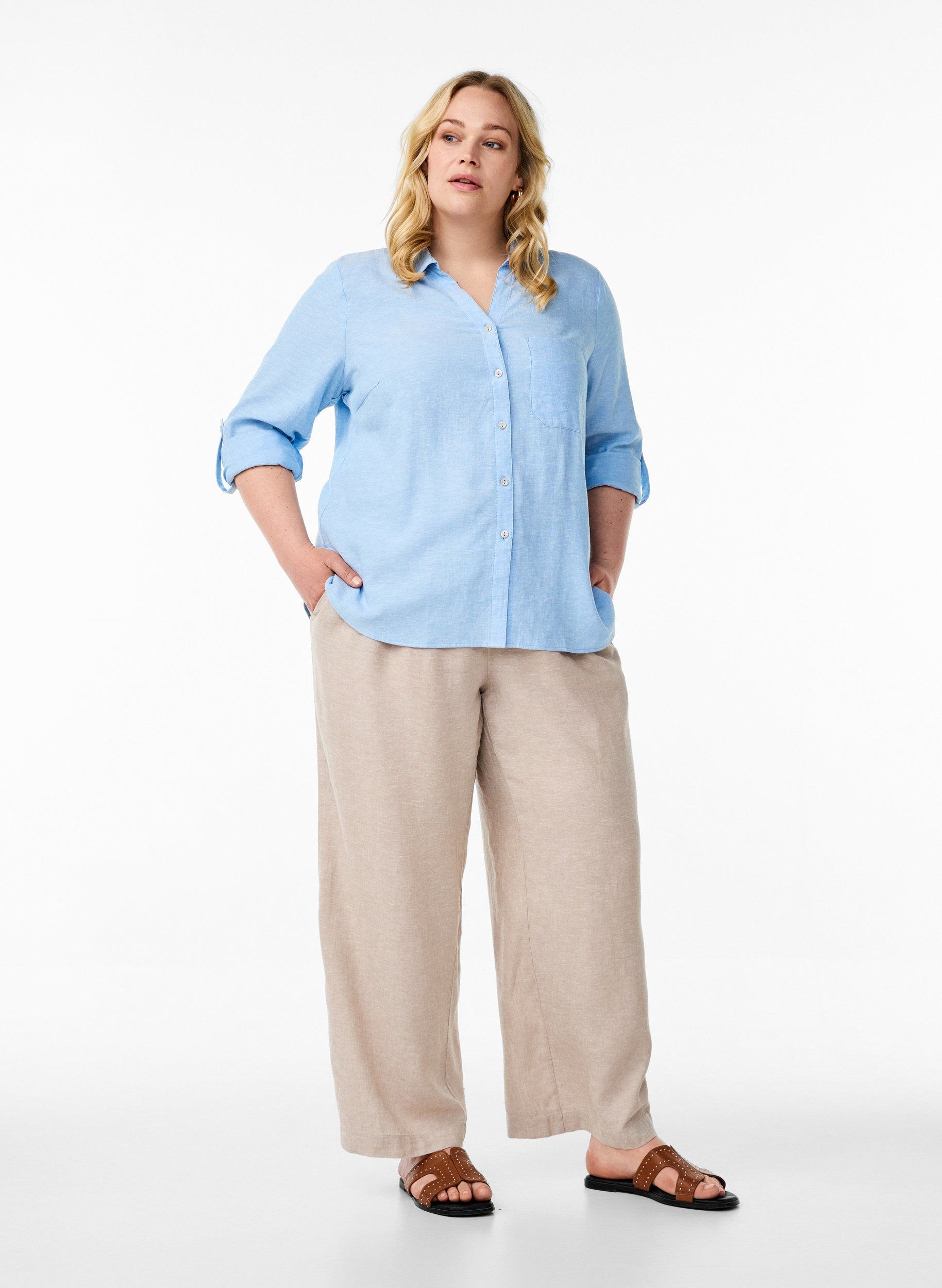 Woman wearing the Zizzi Lina Shirt in Blue and beige pants on a white background